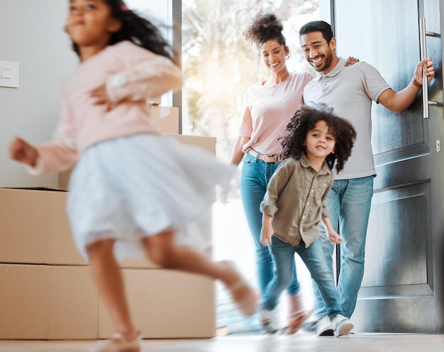 Photo heureux déménagement et parents avec enfants courant dans leur nouvelle maison familiale moderne avec enthousiasme sourire de bonheur et jeune mère et père regardant leurs enfants sauter en mouvement flou chez eux