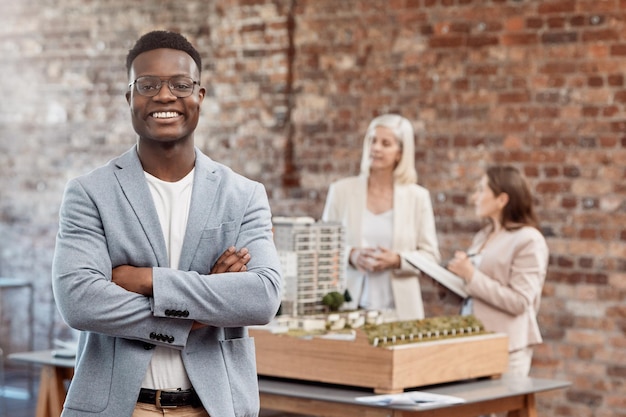 Heureux directeur souriant et confiant debout avec les bras croisés tout en travaillant au bureau au travail