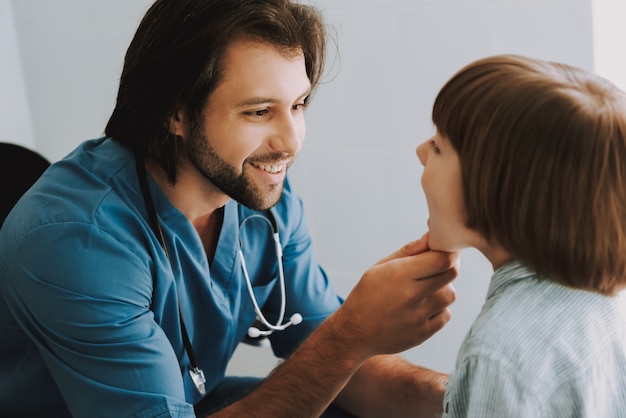 Heureux docteur pratiquant examinant la gorge des enfants