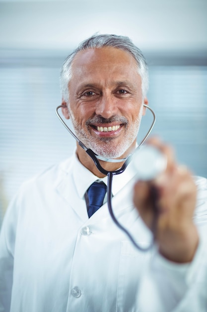Heureux docteur tenant un stéthoscope en clinique