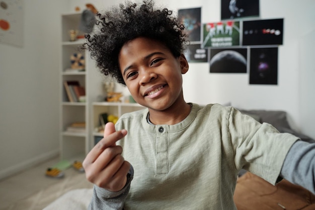 Heureux écolier afro-américain regardant la caméra tout en faisant du selfie