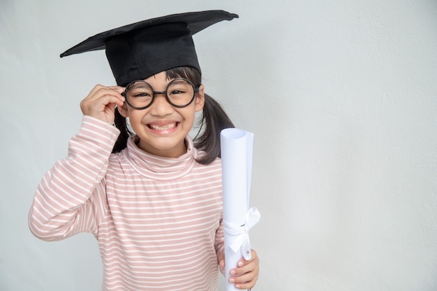 Photo heureux écolier asiatique diplômé en chapeau de graduation