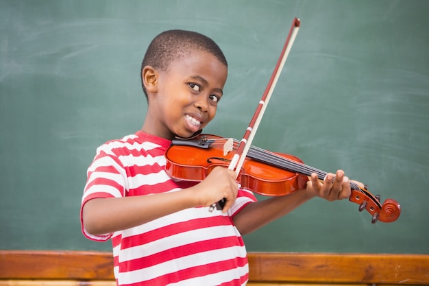 Heureux élève jouant du violon dans la salle de classe