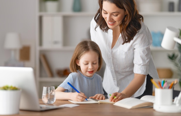 Heureux enfant et adulte sont assis au bureau Fille faisant ses devoirs ou éducation en ligne