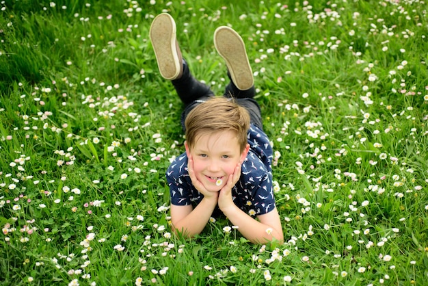 Heureux enfant allongé sur une pelouse fleurie