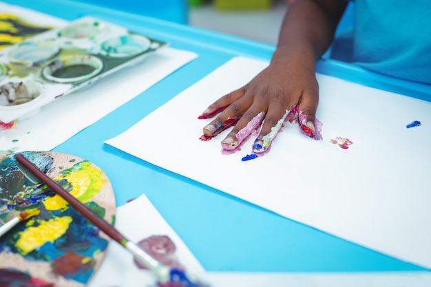 Heureux enfant appréciant peinture avec ses mains à leur bureau