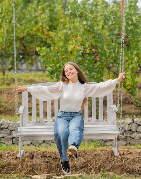 Heureux enfant assis sur la balançoire dans le parc, l'été.