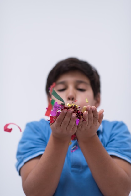 Heureux enfant célébrant la fête avec des confettis soufflants