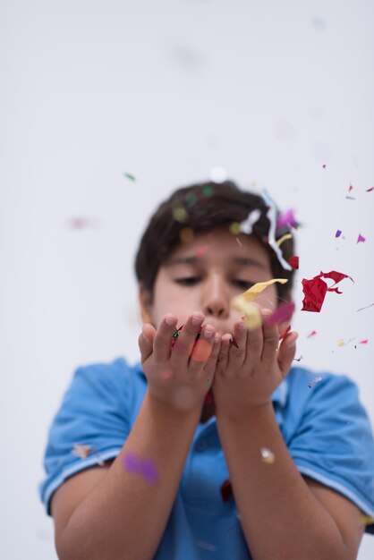 Heureux enfant célébrant la fête avec des confettis soufflants