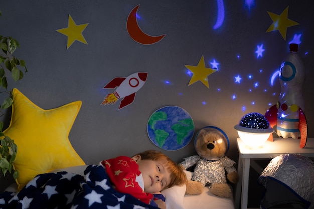 Heureux enfant dormant avec une fusée jouet et un ours en peluche. Kid prétend être astronaute. Imagination et concept de rêve d'enfants
