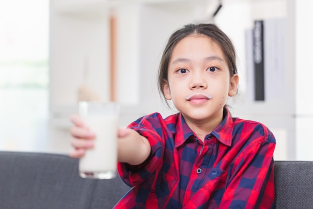 Heureux enfant fille boit du lait Portrait d'un petit enfant asiatique mignon tenant une tasse de lait dans la cuisine