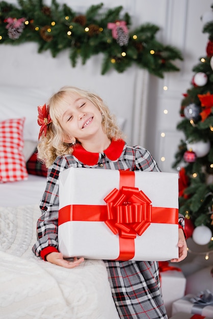 Heureux enfant fille excitée tenant la boîte-cadeau de Noël.