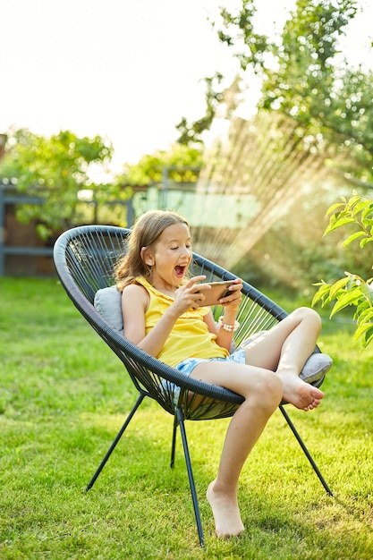 Heureux enfant fille jouant au jeu sur téléphone mobile dans le parc en plein air