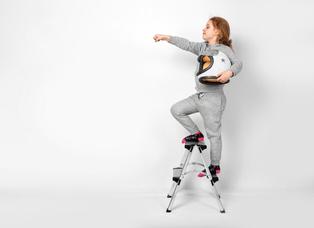 Heureux enfant fille vêtue d'un costume d'astronaute debout sur un escabeau.