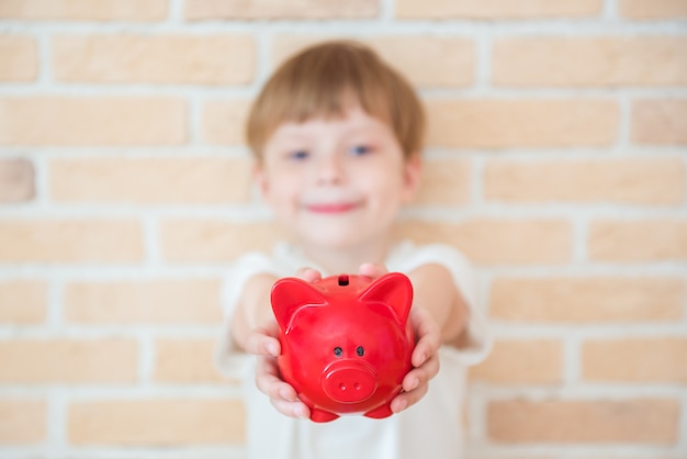 Heureux enfant garçon se tient avec une tirelire dans ses mains. Concept d'entreprise de réussite, de création et d'innovation