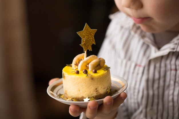 Heureux enfant garçon tenant un gâteau.