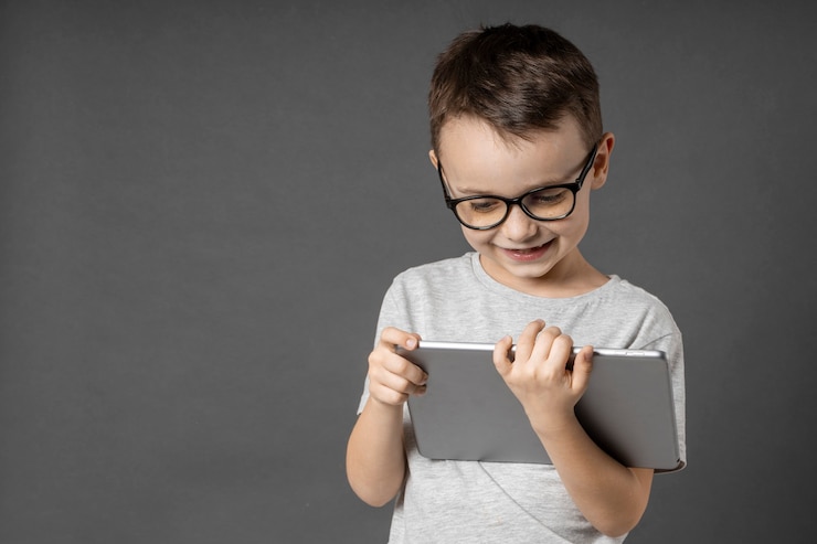 Photo heureux enfant garçon tenant une tablette ipade pour votre information sur le fond bleu