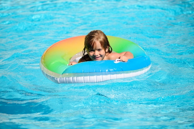 Heureux enfant jouant avec un anneau de bain coloré dans la piscine le jour de l'été Jouets aquatiques pour enfants Les enfants jouent dans un complexe tropical Vacances à la plage en famille
