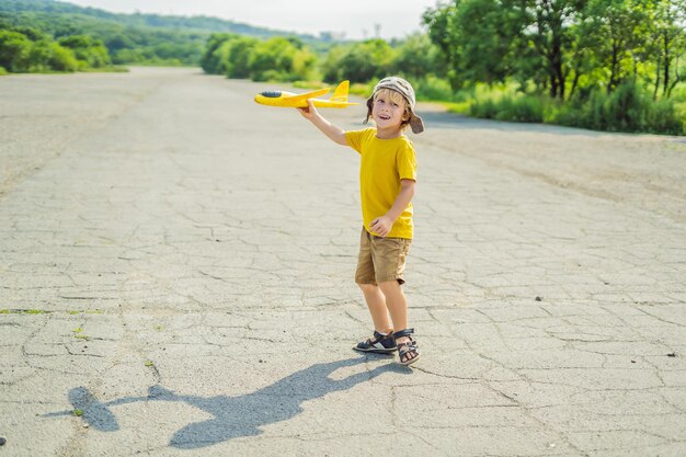 Heureux enfant jouant avec un avion jouet sur fond de piste ancienne Voyager avec le concept d'enfants