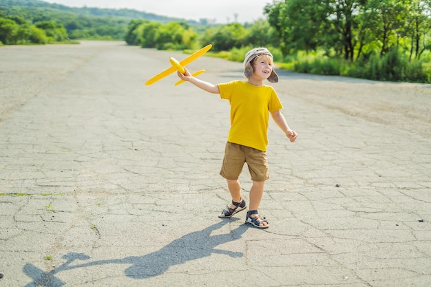 Heureux enfant jouant avec un avion jouet sur fond de piste ancienne Voyager avec le concept d'enfants