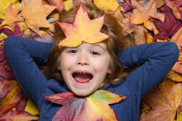 Heureux enfant jouant dans le parc d'automne sur la nature à pied à l'extérieur