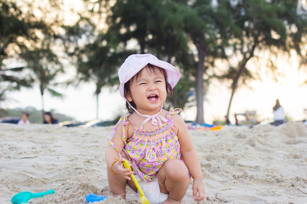 Heureux enfant jouant avec du sable à la plage en été