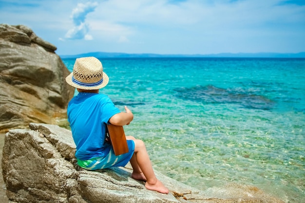 Heureux enfant jouant de la guitare au bord de la mer Grèce sur fond de nature