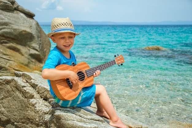 Heureux enfant jouant de la guitare au bord de la mer