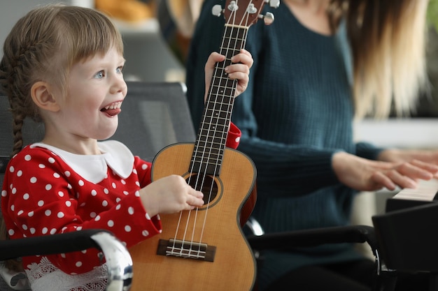 Heureux enfant jouant de la guitare et mère jouant du piano en concert à la maison