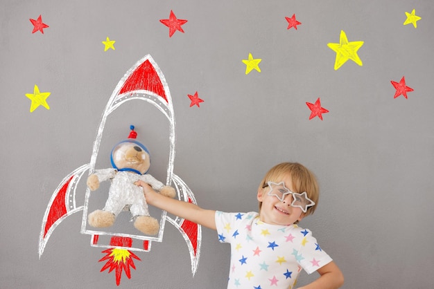 Heureux enfant jouant avec un ours en peluche à la maison. L'enfant fait semblant d'être astronaute. Concept de rêve d'imagination et d'enfants