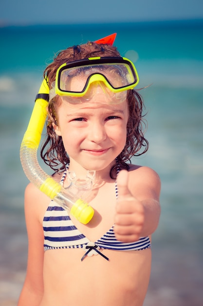 Heureux enfant jouant sur la plage Kid montrant les pouces vers le haut concept de vacances d'été