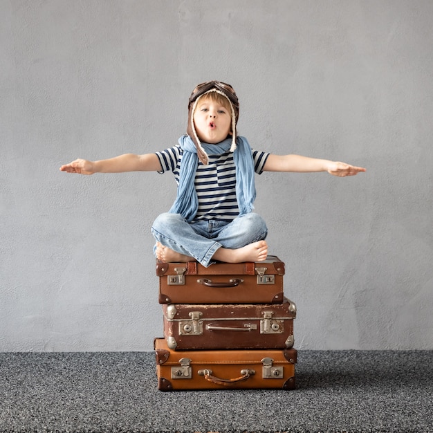 Heureux enfant jouant en plein air. Enfant souriant rêvant de vacances d'été et de voyages. Concept d'imagination et de liberté