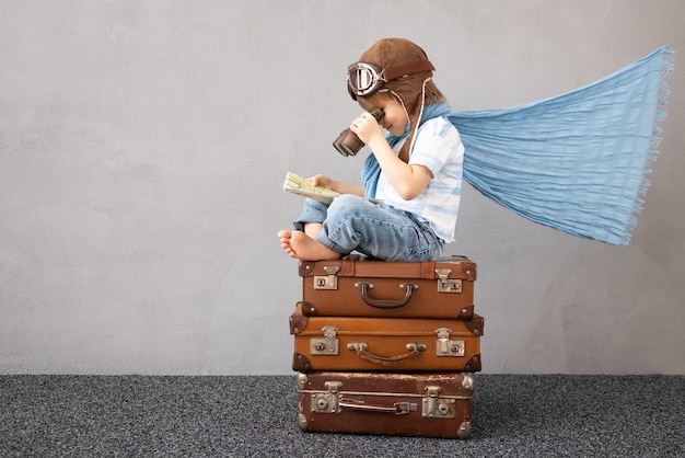 Heureux enfant jouant en plein air. Enfant souriant rêvant de vacances d'été et de voyages. Concept d'imagination et de liberté