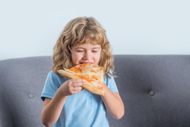 Heureux enfant mordant une grosse tranche de pizza fraîchement préparée Petit garçon mangeant de la pizza Mignon petit garçon mange des pizzas Heureux beau jeune garçon adolescent tenant une tranche de pizza Enfant délicieuses pizzas italiennes