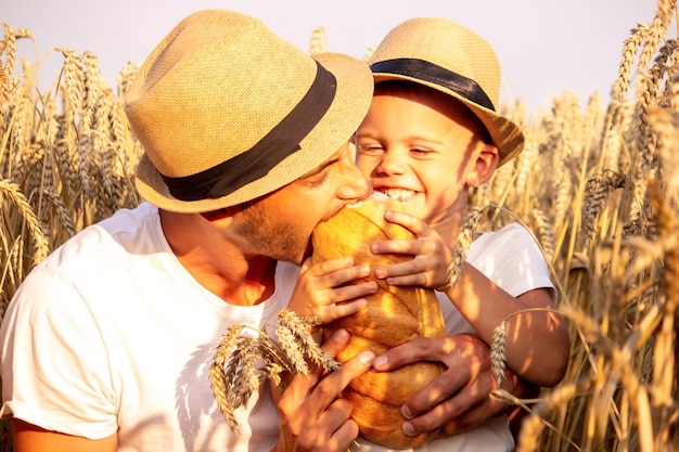 Heureux enfant et père dans le champ de maturation du blé garçon et papa voyagent à travers le champ chi ...