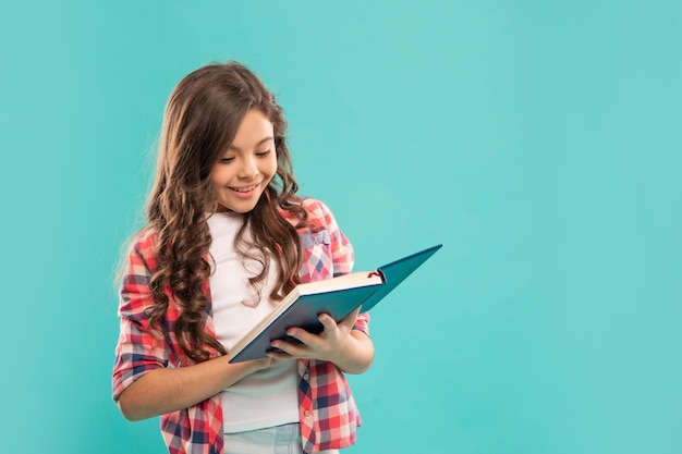 Heureux enfant prenant des notes sur fond bleu avec copie espace école