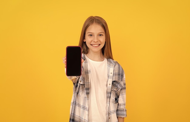 Heureux enfant présentant le produit de l'écran d'affichage du smartphone moderne pour la publicité de l'espace de copie