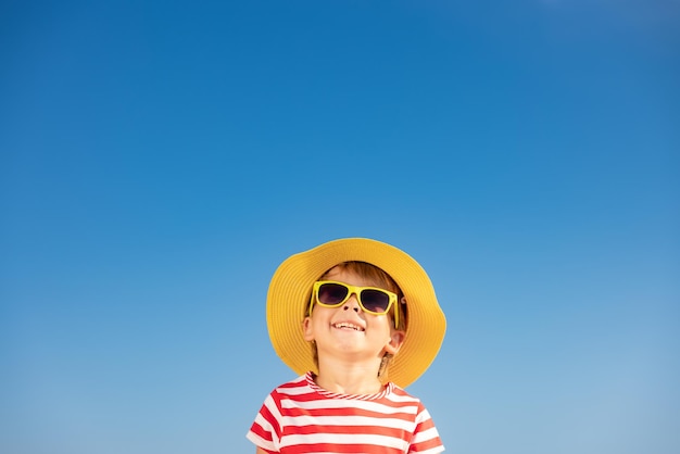 Heureux enfant s'amusant en plein air sur fond de ciel bleu. Portrait d'enfant souriant en vacances d'été. Concept de liberté et de voyage