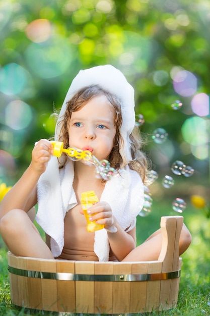 Heureux enfant se baignant à l'extérieur sur l'herbe verte dans le jardin de printemps