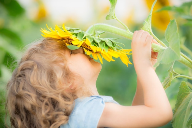 Heureux enfant sentant le beau tournesol à l'extérieur dans le champ de printemps