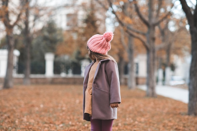 Heureux enfant souriant porter une veste et un chapeau dans le parc avec des feuilles mortes sur fond de nature Automne