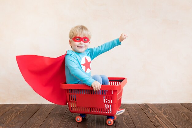 Heureux enfant de super-héros jouant à la maison.