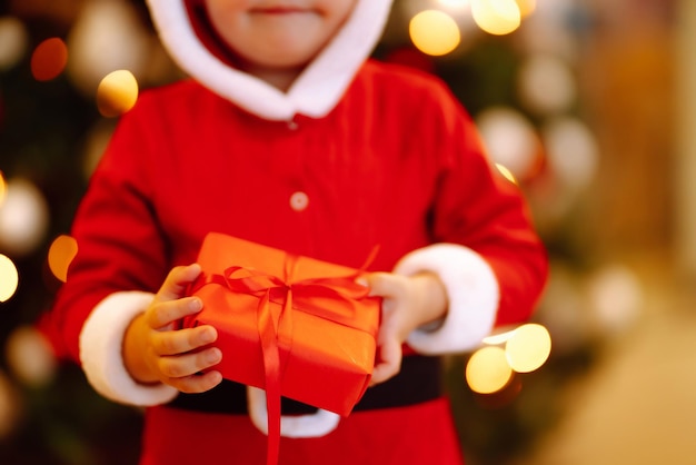 Heureux enfant tenant une boîte-cadeau rouge sur les feux de fond