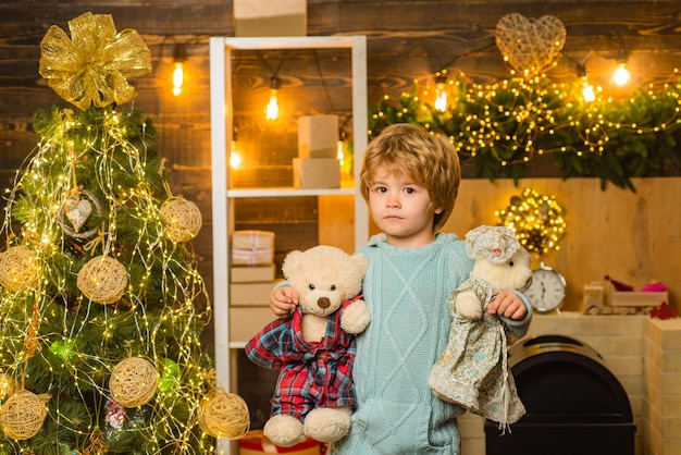 Heureux enfant tenant deux ours en peluche avec les deux mains Nouvel an enfants Joyeux Noël et Joyeuses Fêtes