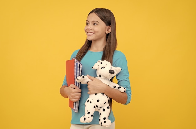 Heureux enfant va faire ses devoirs avec un étudiant adolescent bloc-notes tenant un chien jouet