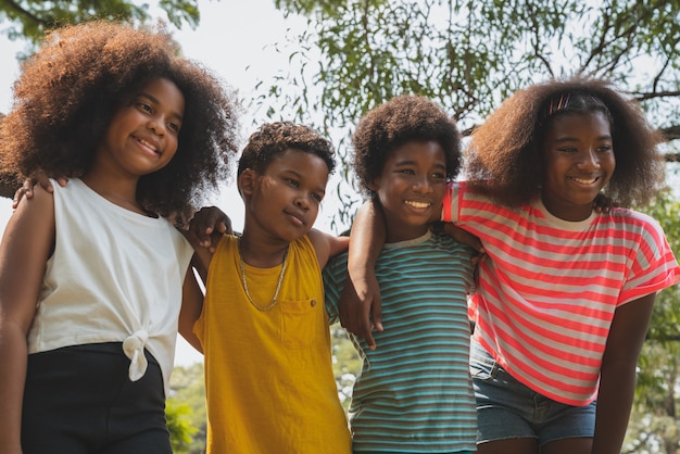 Heureux enfants africains souriant et embrassant ensemble dans le parc