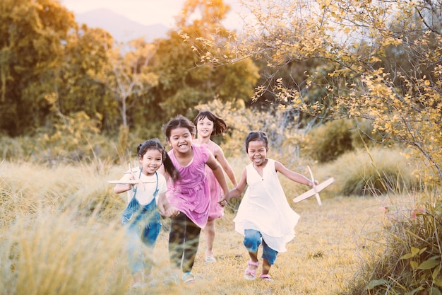 Heureux enfants asiatiques s&#39;amuser à courir et jouer avec avion jouet en papier