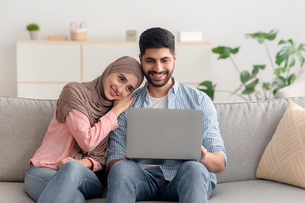 Heureux époux du Moyen-Orient utilisant un ordinateur portable assis à la maison