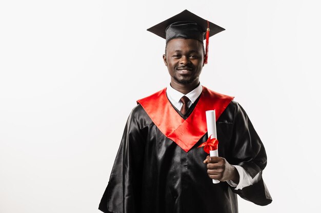 Heureux étudiant africain en robe de graduation noire et casquette lève le diplôme de maîtrise au-dessus de la tête sur fond blanc Un homme africain diplômé est diplômé de l'université et célèbre la réussite scolaire