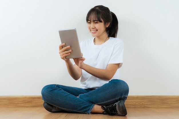 Heureux étudiant asiatique assis avec l'utilisation de la tablette à la maison